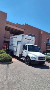 A white “Thanks for the Help” moving truck parked near the entrance of a hotel or resort building on a sunny day.