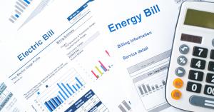 Image shows a calculator and a stack of electricity and energy bills