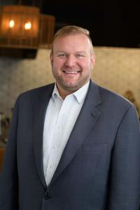 Man smiling in suit standing next to counter in commercial kitchen