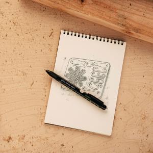 From Flowers to Function: Wirecutter Highlights the Rise of Practical Valentine’s Gifts 7 Lucky Jack 9-in-1 Builder’s Pen multi-tool resting on a notepad with a hand-drawn design sketch, emphasizing its role as an everyday carry writing and utility tool.