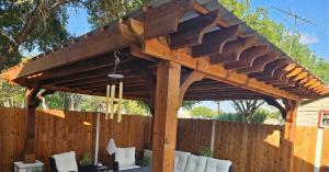 Pergola Depot Big Kahuna PLUS Cedar Covered Pergola with premium metal roofing providing complete protection from rain and sun on backyard patio