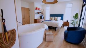 A large tub with a bed in the background along with a dresser in a birth suite.