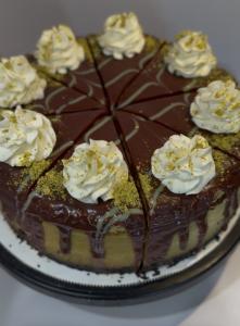Chocolate-drizzled cheesecake topped with whipped cream rosettes, sliced into individual pieces on a serving tray.