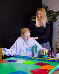 Artist Clara Woods painting at Rogue Collective with her mother, Betina Genovesi, strategist and curator of Clara Woods Collection and The Inclusion Matters Movement.