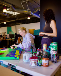 Artist Clara Woods paints a colorful abstract canvas at Rogue Collective in Newport Beach, Calif.