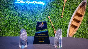 Crystal awards trophies for GlowRow on a black table, featuring Innovative Experience of the Year (Texas/USA) and others, against a green foliage wall with 
