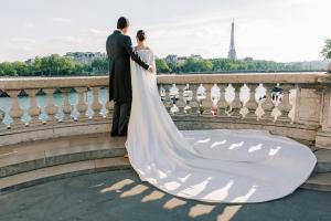 A bride and groom overlooking the Eiffel Tower during a luxury Paris destination wedding by Soirées CaféDelux Events, highlighted by Ageless Living Manhattan Magazine.