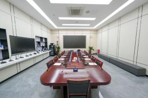 A high-angle photograph of a modern, well-equipped conference room exhibit at the ITC headquarters. The space has gray marble floors and light-paneled walls. A long, dark wood conference table takes center stage, lined with numerous ITC digital conference
