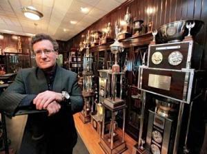 Dr. Robert Goldman photographed in his trophy room surrounded by awards and accolades celebrating achievements in anti-aging medicine, sports performance, fitness leadership, and worldwide health and wellness advocacy.