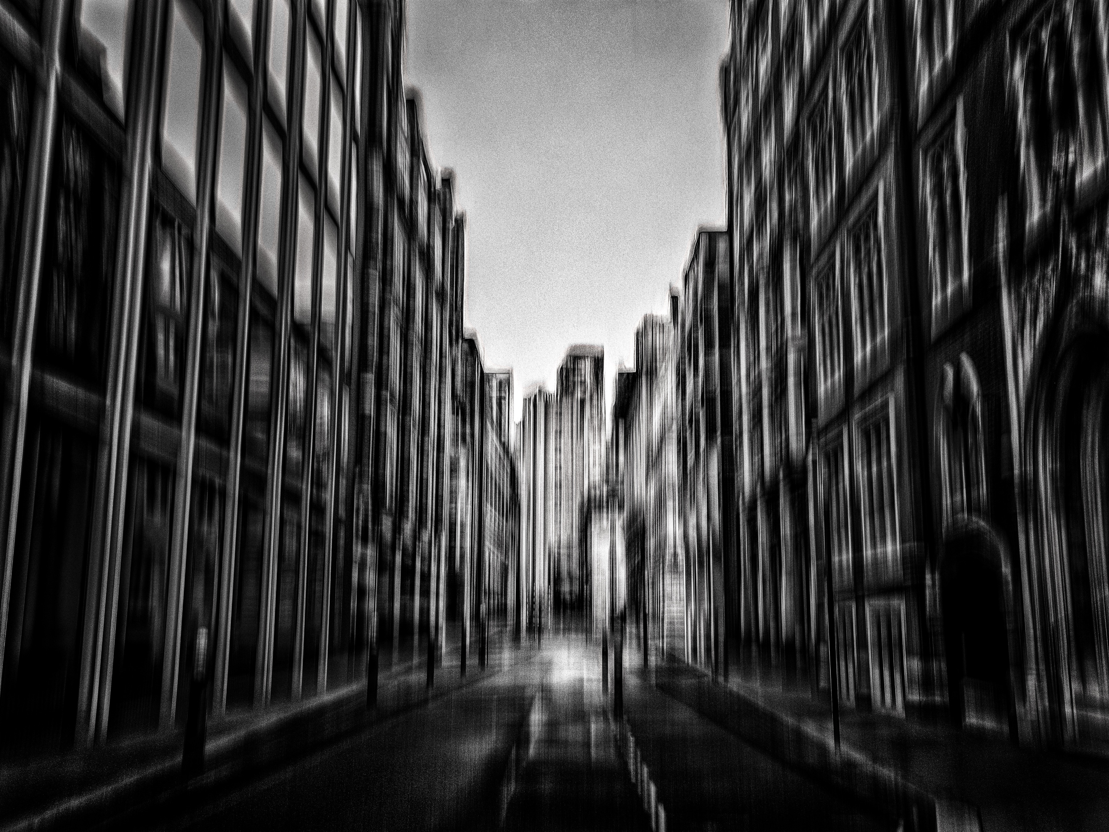 Urban Canyon – Black and white abstract ICM photograph by Antonina Minova of city architecture with motion blur, strong contrast, shadow, and light.