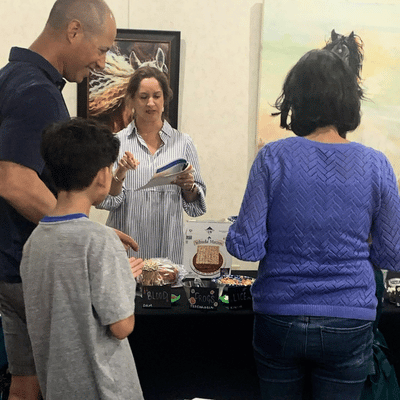 Four people interact at a stall with jars labeled