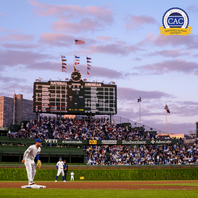 Baseball game at Wrigley Field with players on field and fans filling the stands at dusk under a partly cloudy sky.