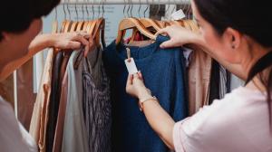 Women browsing apparel labels on a rail of clothing