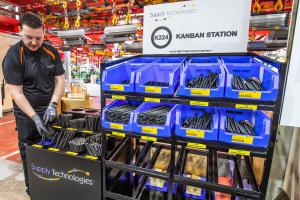 Supply Technologies employee replenishing assembly components at a Kanban inventory station in a manufacturing facility.