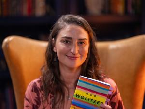 Sara Bareilles poses on the set of Books That Changed My Life, holding a copy of The Interestings by Meg Wolitzer.