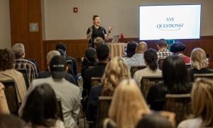 A presenter speaks beside a projection screen while attendees sit in rows during a Small Business Expo workshop.