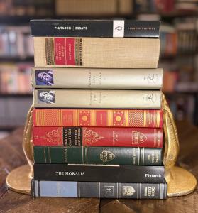 A stack of classic hardcover books including volumes of Plutarch