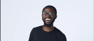 Tim Salau, Mr Future of Work Smiling while wearing a black t-shirt and black glasses