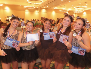 W.B. Ray High Fighting Texan All-American Cheerleaders to Perform in the Pearl Harbor Memorial Parade in Honolulu, HI 10 Image of five Ray High School cheerleaders in animal print costumes, holding up UCA medals.