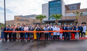 UTRGV President Guy Bailey cuts a large orange ribbon with oversized scissors at the grand opening of the Cancer and Surgery Center in McAllen, Texas.